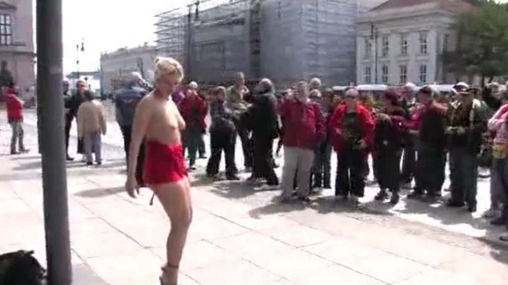 Beautiful blonde girl naked and restrained in public with crowd of onlookers